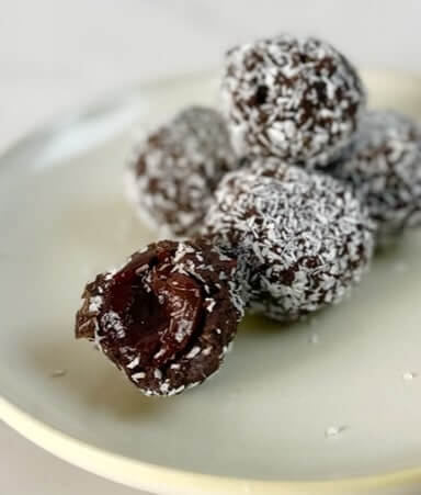 Chocolate balls with cherries covered in coconut flakes