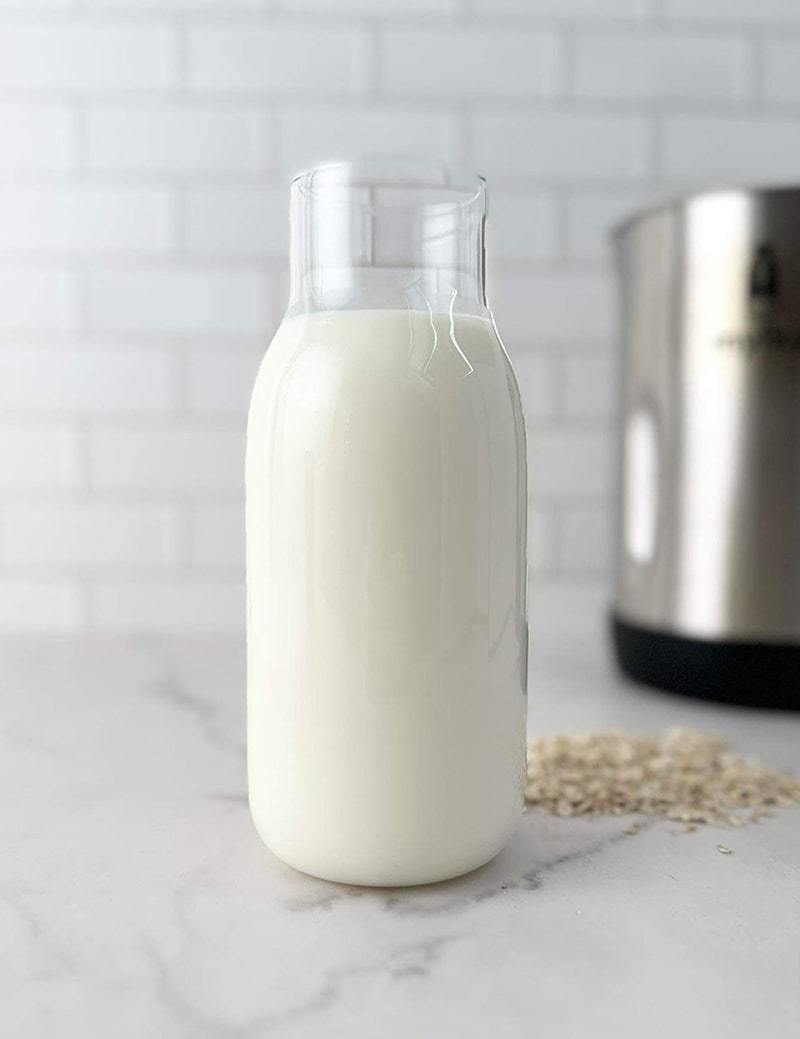 Bottle of freshly made plant-based milk on a countertop with a kitchen appliance in the background