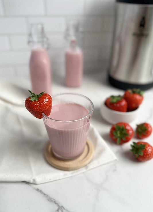 Strawberry plant-based milk in a glass with fresh strawberries