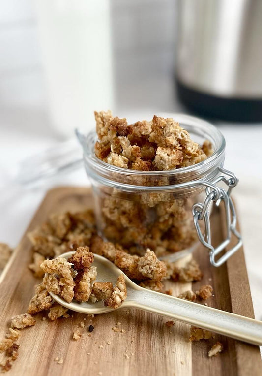 Jar of homemade almond pulp granola with oats, honey, and cinnamon